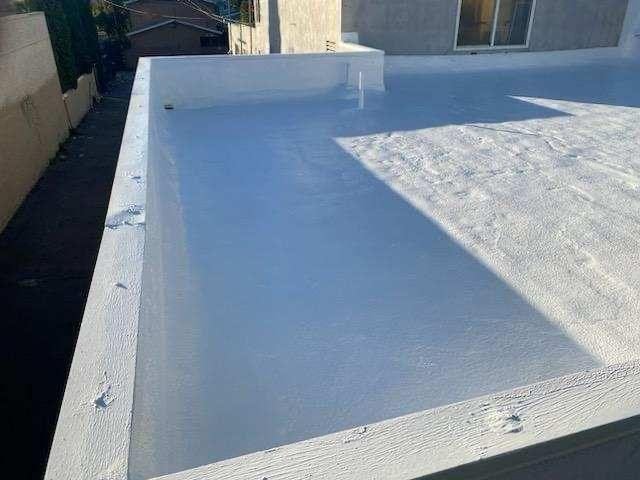 White elastomeric coating on a flat roof with parapet walls