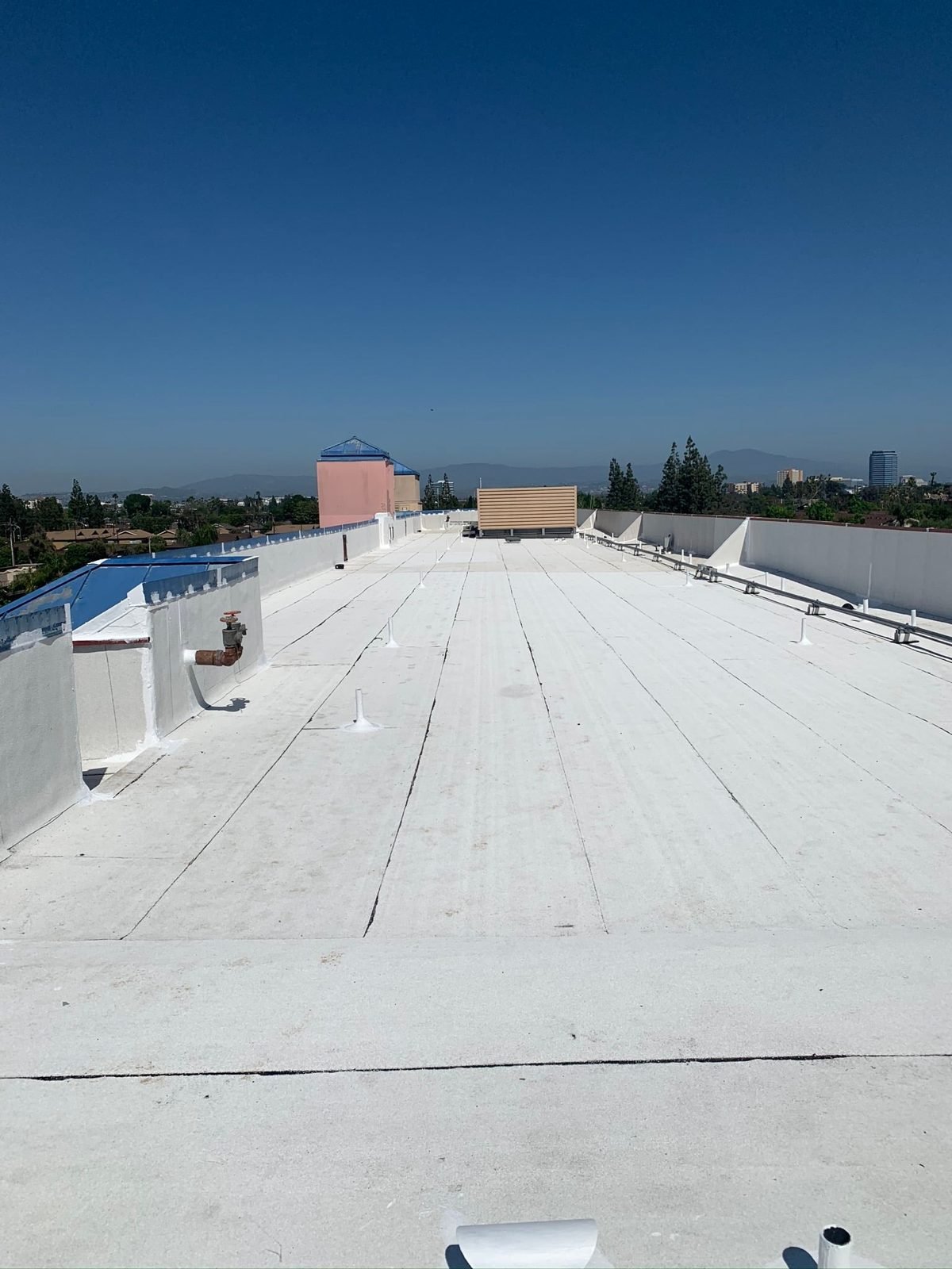 White reflective coating on a low-slope roof with the Los Angeles skyline behind