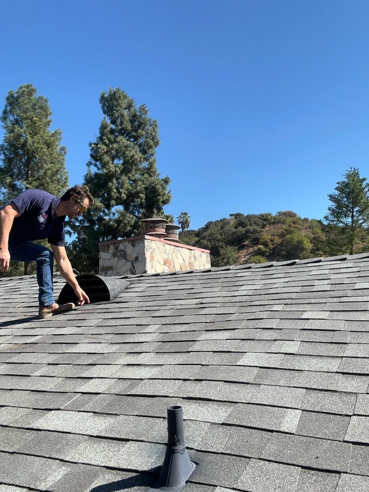 Roofer inspecting flashing and penetrations on a Valley roof