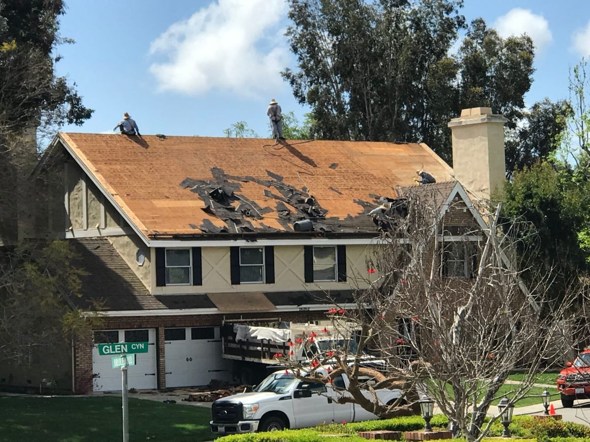Crew stripping a two-story home to the deck during a re-roof