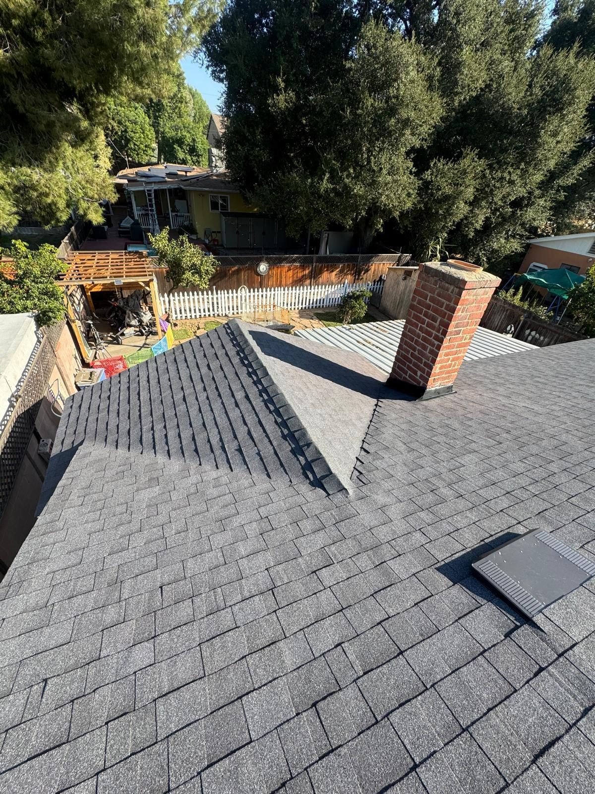 New architectural shingle wrapping a brick chimney with new flashing