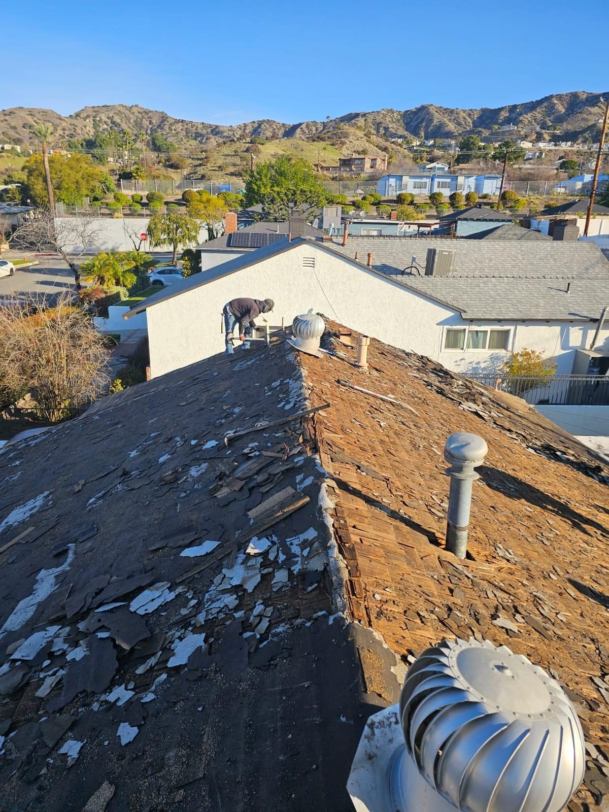 Worn, cracked shingles before tear-off on a ranch home